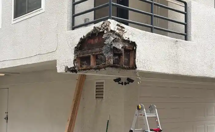 Exposed dry rot and broken stucco at balcony corner with temporary wood shoring, Marina del Rey structural damage assessment