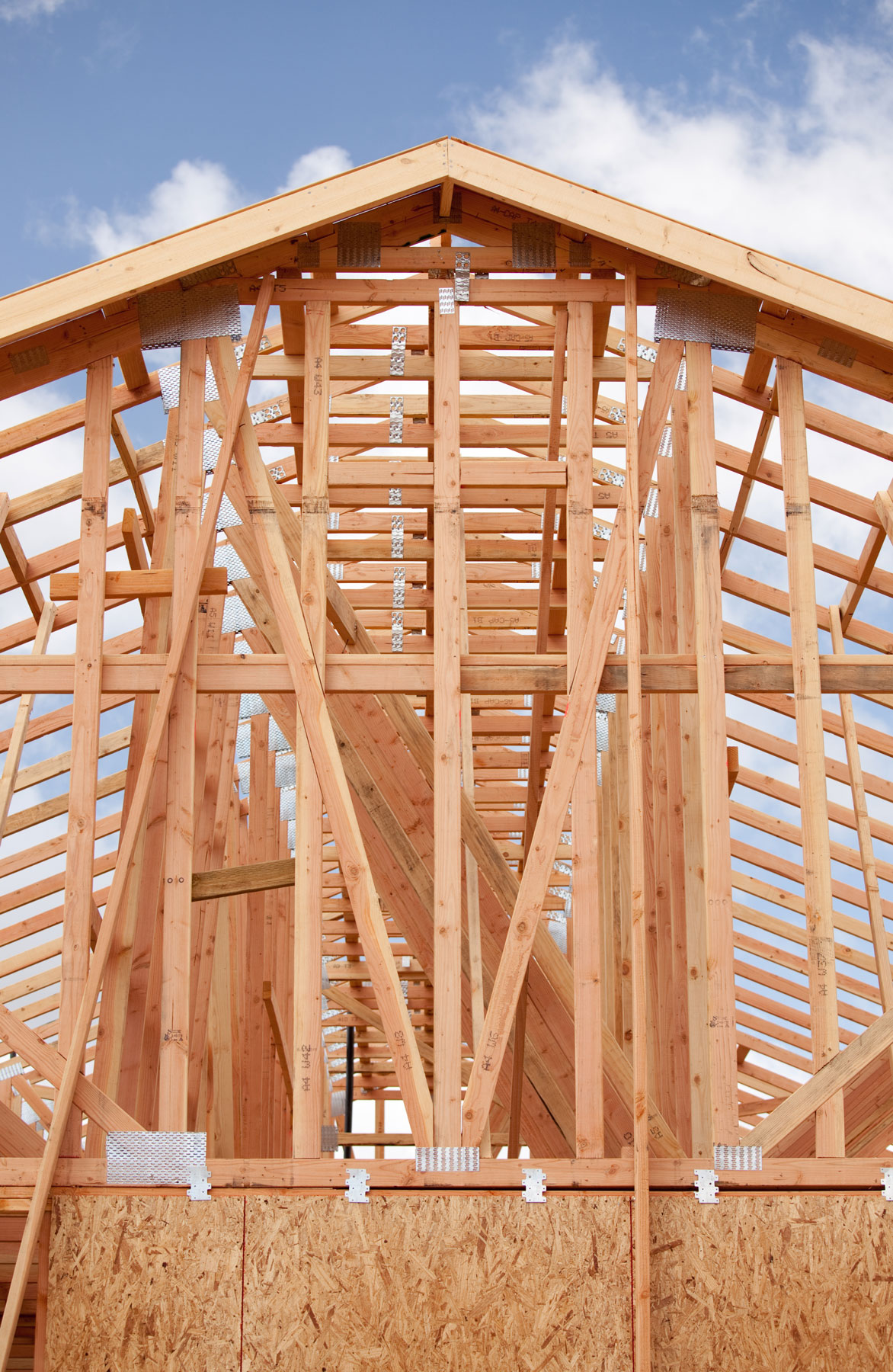 Structural framing for a custom home under construction showing roof trusses, engineered framing, and load-bearing walls before roofing and exterior finishes are installed.