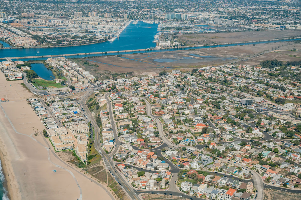 Aerial view of Playa del Rey, California, showing coastal homes, Ballona Wetlands, Marina del Rey Harbor, and the Pacific coastline.