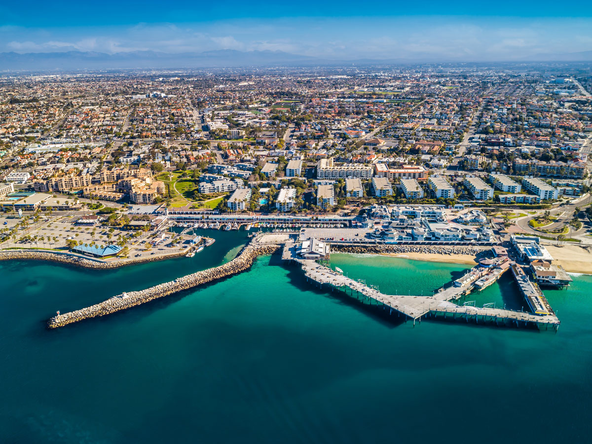 Wide aerial view of Redondo Beach, California, showing King Harbor, coastal residential neighborhoods, the marina, and the surrounding South Bay community.
