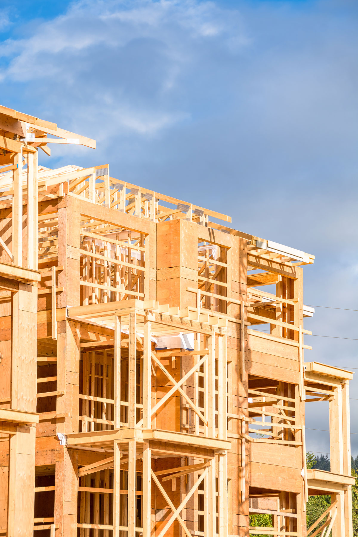 Residential home framing under construction with exposed wood framing, roof structure, and second-story exterior walls before exterior finishes.